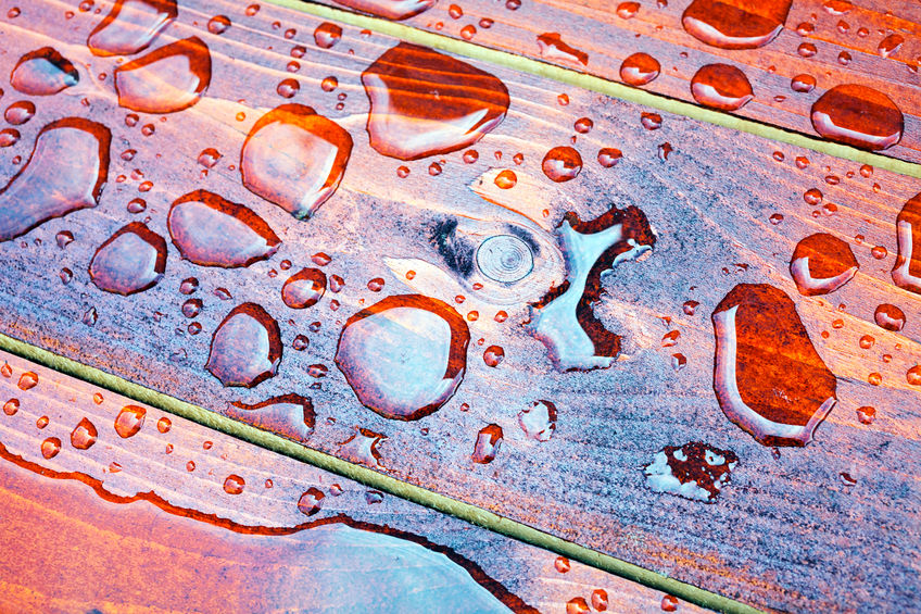 closeup of drops of water on brown wooden floor